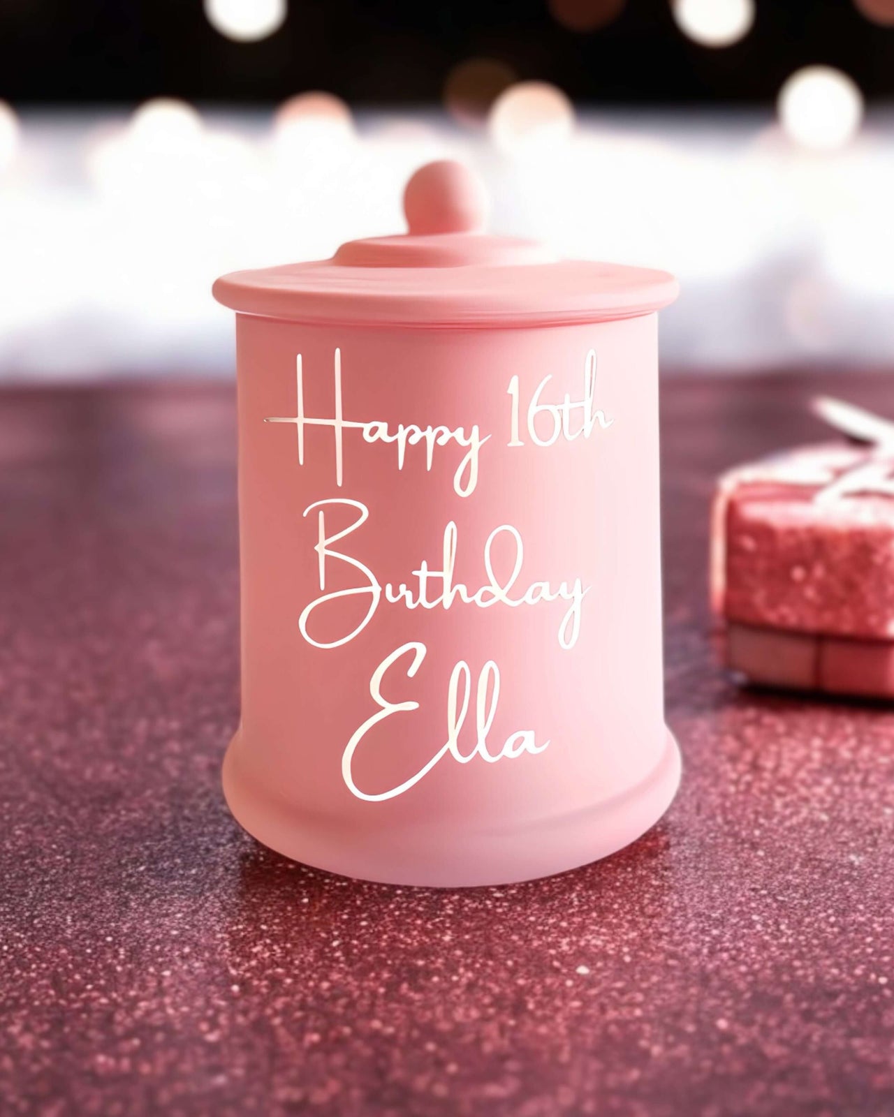 Personalised pink birthday candle with gold writing that reads “Happy 16th Birthday Ella”.