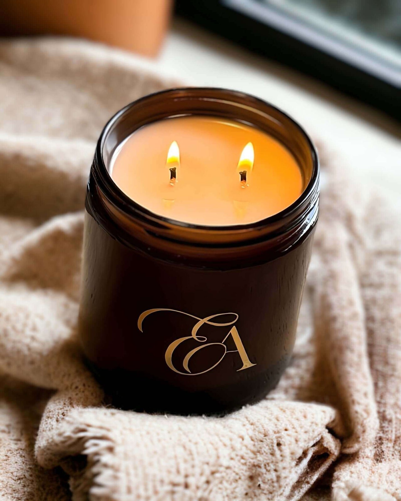 A twin flame amber glass candle burning brightly